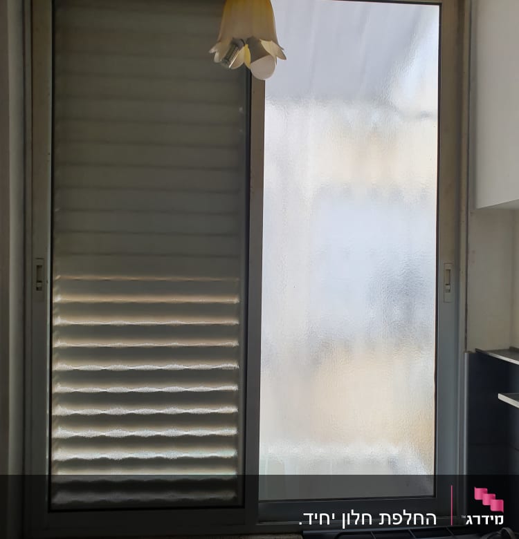 חלון זכוכית עם תריסים סגורים ומנורה תלויה